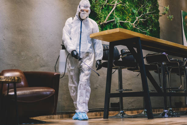 Man in protective suit spraying with disinfectant bar, cafe and restaurant interiors to prevent further spread of the coronavirus